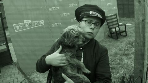 Joe dressed as a security guard holding a dog.