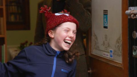 A young girl with a red hat on laughing.