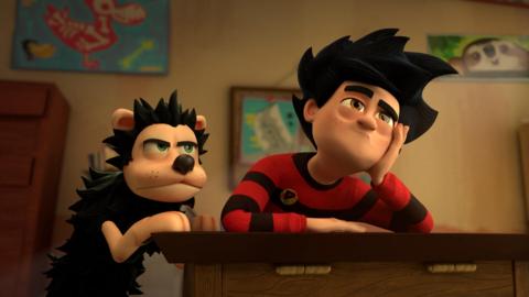 Dennis and Gnasher at a school desk looking bored.