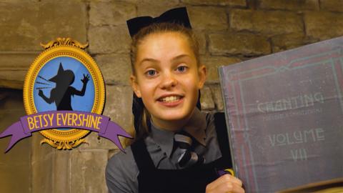 A girl standing next to a desk in a castle, holding up a book about chanting, Ethel Hallow.