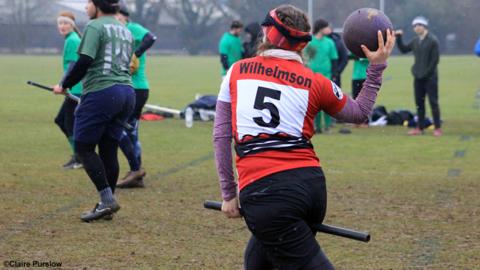 A grl playing quidditch, about to throw a ball.