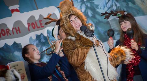 A boy dressed as a reindeer singing his heart out.