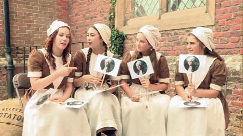 Four girls sat in victorian style dresses, (the Hetty Feather cast).