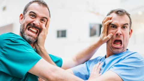 Two male doctors pushing their faces away from each other.