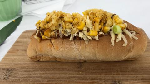 A hot dog on a chopping board.