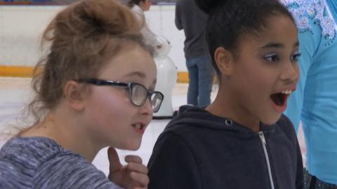 Two girls at an ice rink looking excited.