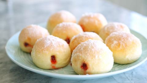 Doughnuts on a plate filled with strawberry jam.