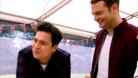 Sam and Mark leaning over a counter in the Bake Off tent.