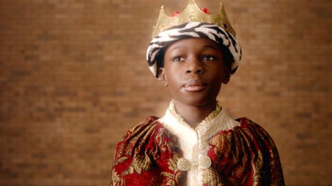 Cedric is posing in a King's costume.