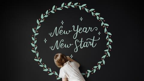 Girl writing on chalkboard writing New Years!