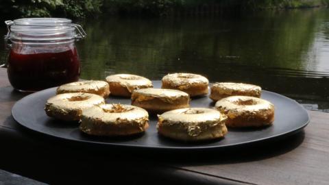 A plate with some gold topped doughnuts.