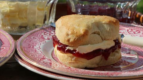 A heart shaped scone with jam and cream.
