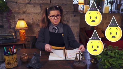 A girl in school uniform at her desk with diary open. Shocked witch emojis next to her. Maud from The Worst Witch.