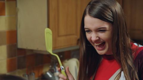 A girl holding a spatula pulls an antagonistic face.