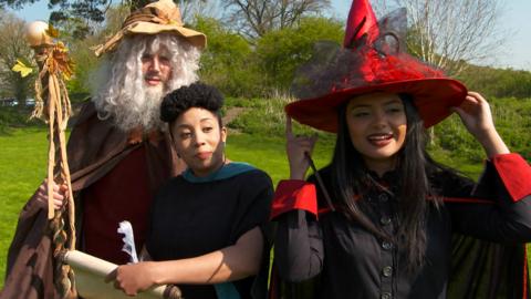 Three adults dressed as wizards.