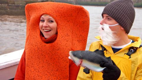 Naomi dressed as a fish finger and Ed dressed as a fisherman holding a fake fish.