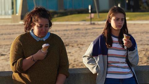 Marnie and Liv stood on a bridge eating ice cream and looking upset.