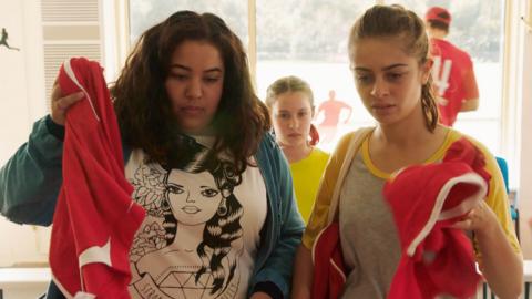 Two girls handing in their football shirts.