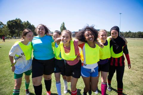 The Mustangs FC female football team stood together with their arms around each other.