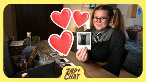 A smiling girl holding a photo of a cat surrounded by heart emojis. Maud from The Worst Witch.