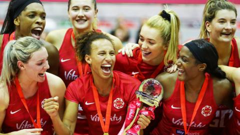 The England netball team celebrating winning a trophy.