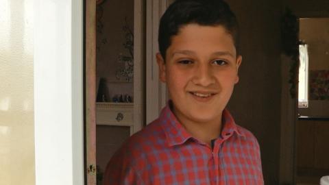 A boy opening the door and smiling.