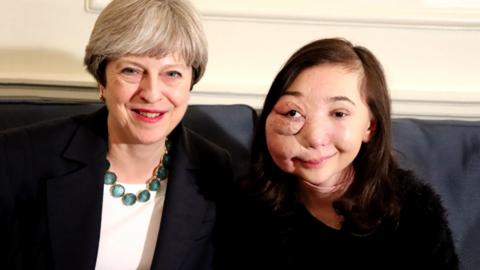 A girl sat next to a woman on a blue sofa, Nikki Lilly and Theresa May.