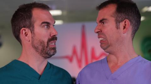 Two men looking at each other while wearing false teeth, Dr. Chris and Dr. Xand.