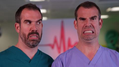 Two men wearing scrubs are smiling with false teeth, Dr. Chris and Dr. Xand from Operation Ouch.