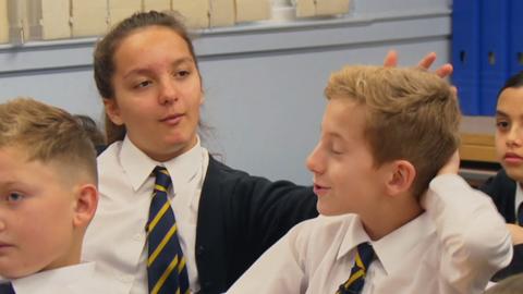 A girl flicking a boy's hair.