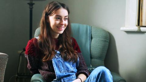 Girl sitting on a chair watching television.