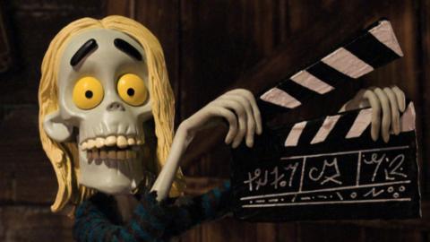 A zombie holding a clapper board.