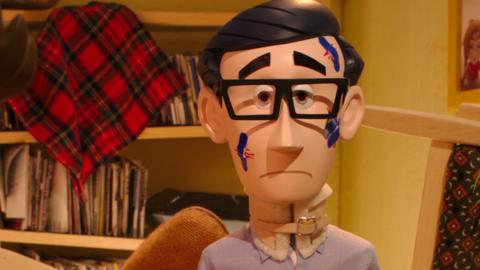 Puppet man with glasses looking sad because of scratches and plasters on this face.