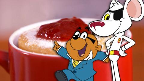 Dangermouse and Penfold stand next to a doughnut in a bright red mug, looking happy. Penfold points at the mug enthusiastically.