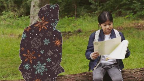 A picture of two people sat in the woods and one of them is silhouetted as Christmas wrapping paper.