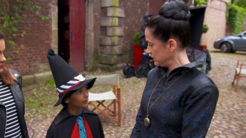 A young girl in a witch's costume looking up as Miss Hardbroom from The Worst Witch.