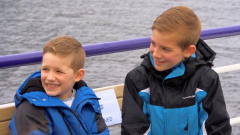 Two boys in blue coats on a boat.