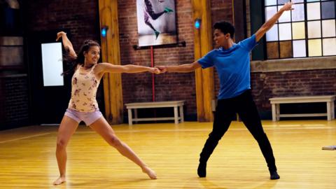 A boy and girl smiling and dancing with each other in a dance studio, Summer and Kingston from The Next Step.