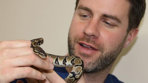 A man holding a small python.