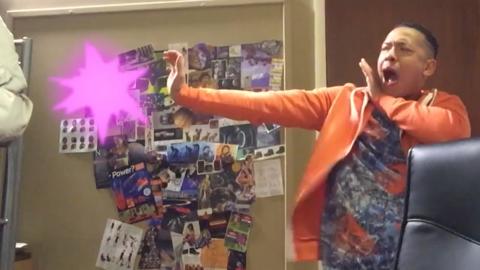 A man mimes a fight action in his room with a pink explosion appearing to come out of his hand.