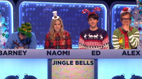 Barney Harwood, Ed Petrie, Naomi Wilkinson and Alex Riley dressed in Christmas outfits and looking thoughtful.