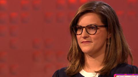 A teacher wearing glasses in front of a red background.