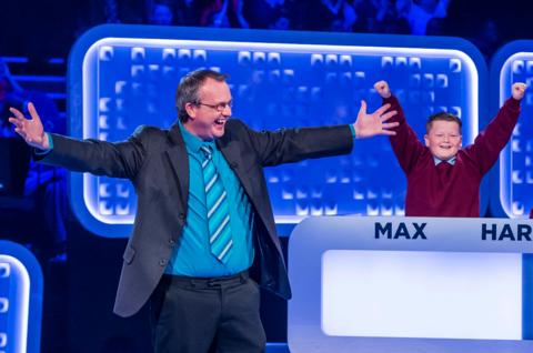 Man in a suit and a boy in a school uniform cheering.