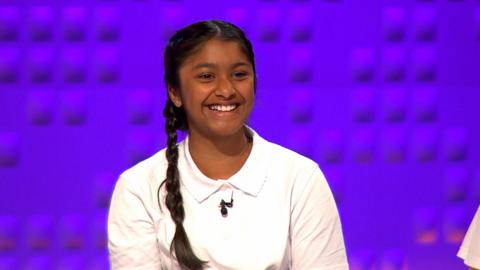 Girl smiles in front of a purple background.