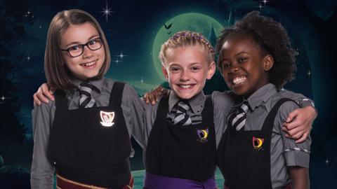 Three girls dressed in school uniforms from Cackle's Academy, Enid, Beatrice and Clarice from The Worst Witch.