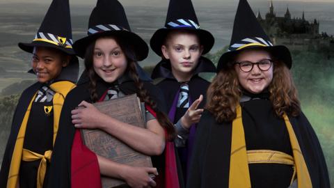 Four witches stand smiling in front of a castle, with the words 'Which Worst Witch character are you?'.