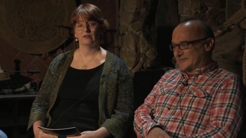 A woman and a man sat in a low lit room next to each other.