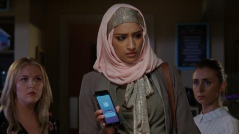 Girl looking distressed holds a phone with a text message displayed.