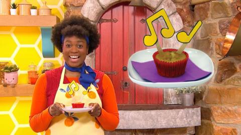 Big Cook is standing holding a plate with a muffin on it. There are musical notes on sticks coming from the muffin.