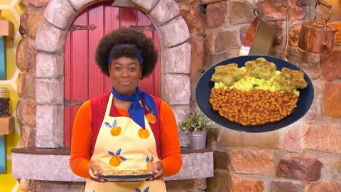 Big Cook is holding a plate of food. The close up of the plate shows beans and scrambled eggs.